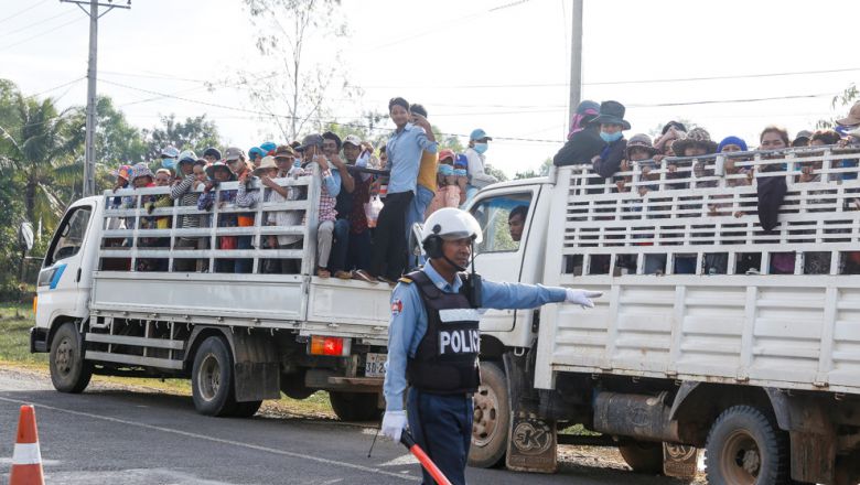 A police officer hails down trucks filled with garment workers early yesterday morning near the Bavet special economic zone in Svay Rieng province.